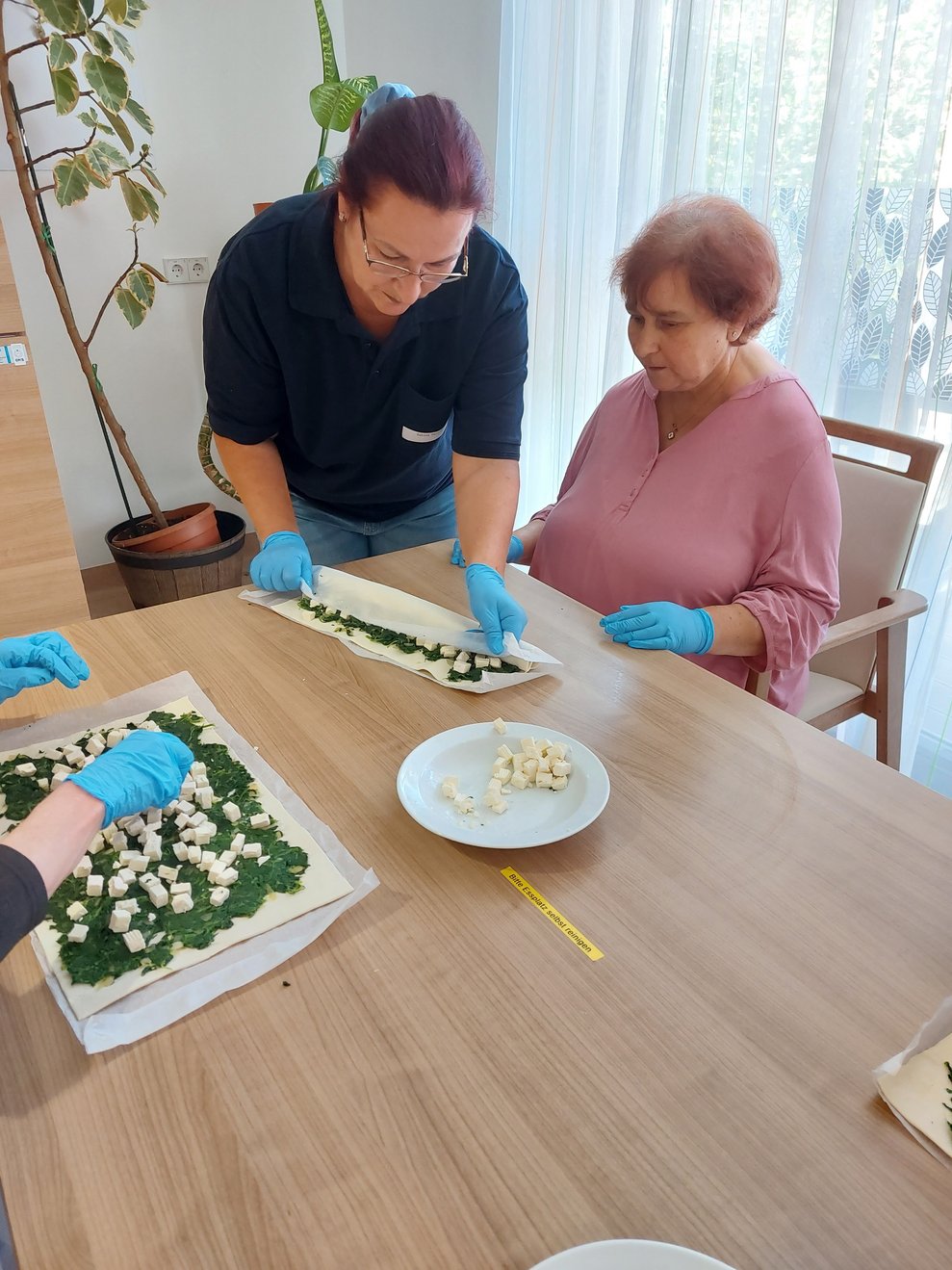 Sabine Wallner und Eveline Gally rollen gemeinsam den zuvor befüllten Strudel ein.